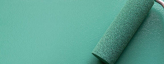 A paint roller covered in teal paint